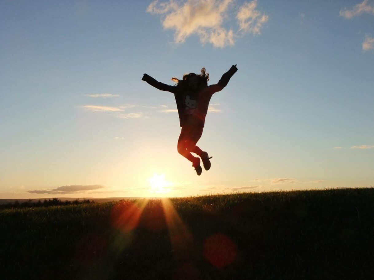silhouette photo of a person jumping nearby green grass field during golden hour