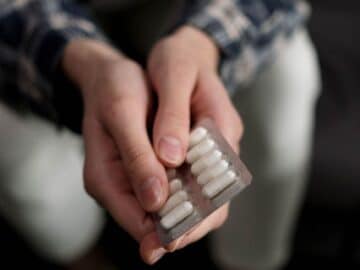 person holding white medicine capsules
