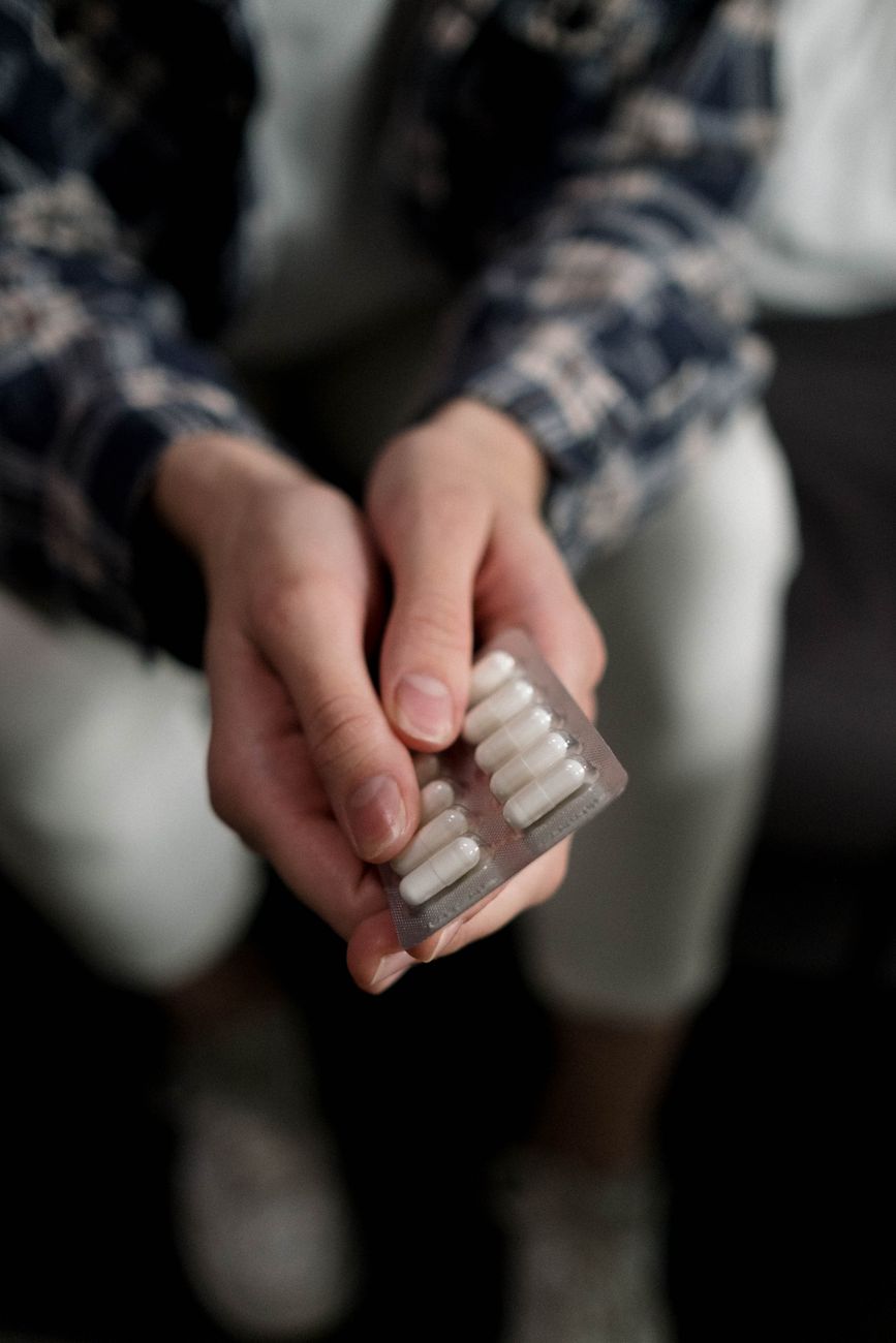 person holding white medicine capsules